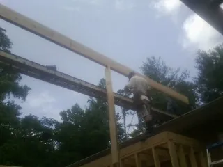 Carpenter setting a ridge beam over a new addition frame — Ice Dam Removal by Roofing Brothers in Grassflat