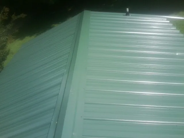 New green metal panels meeting at the ridge of a roof — Flat Roof Repair work by our crew in Grassflat