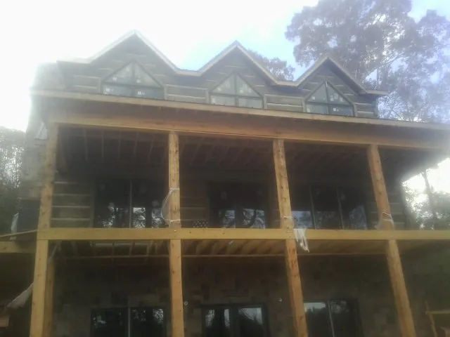 Dormers and porch framing on a large log home under construction — Roof Coating work by our crew in Grassflat