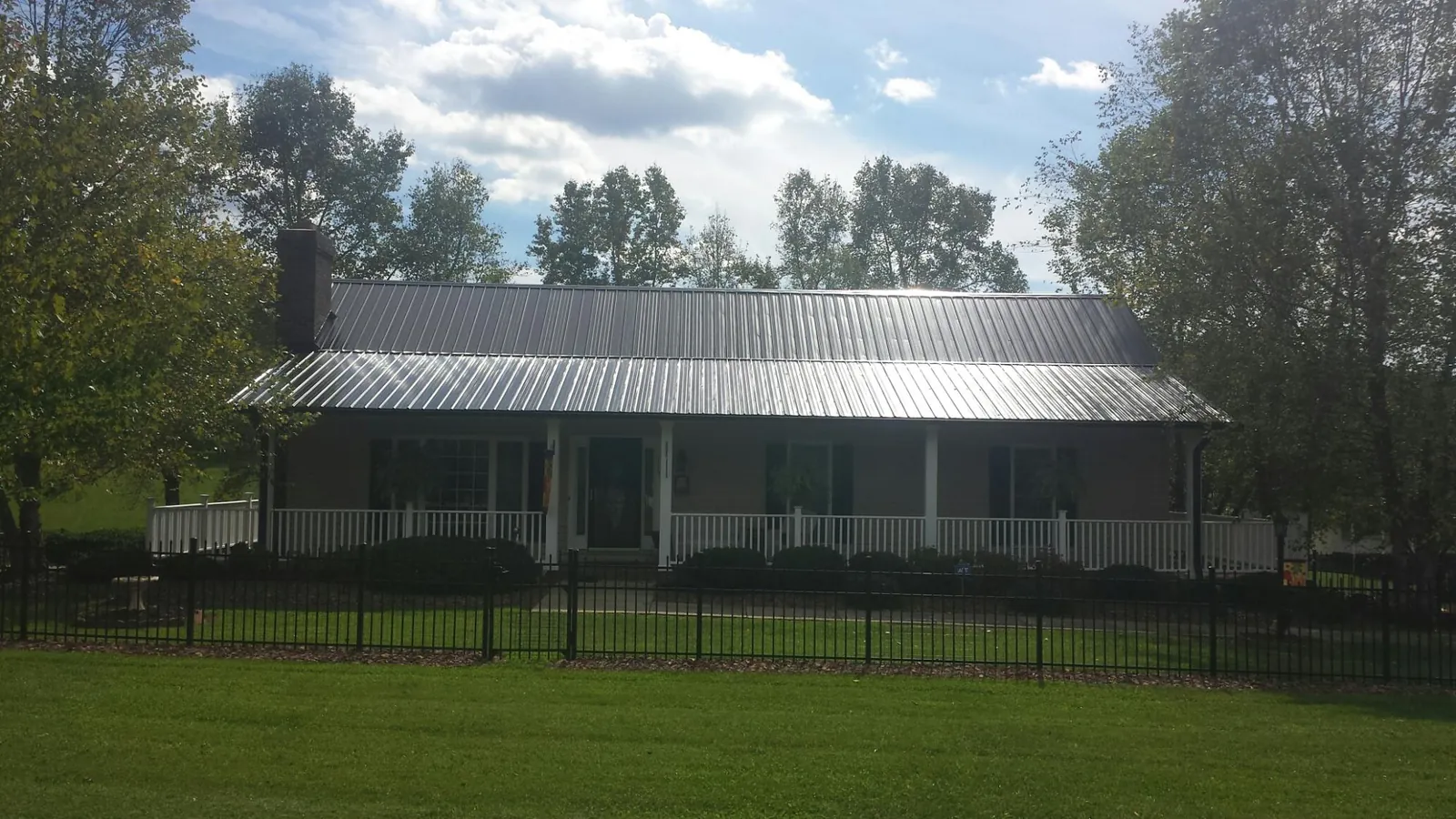 Gray metal roof on a brick ranch with a full width front porch — Gutter Guard Installation work by our crew in Grassflat