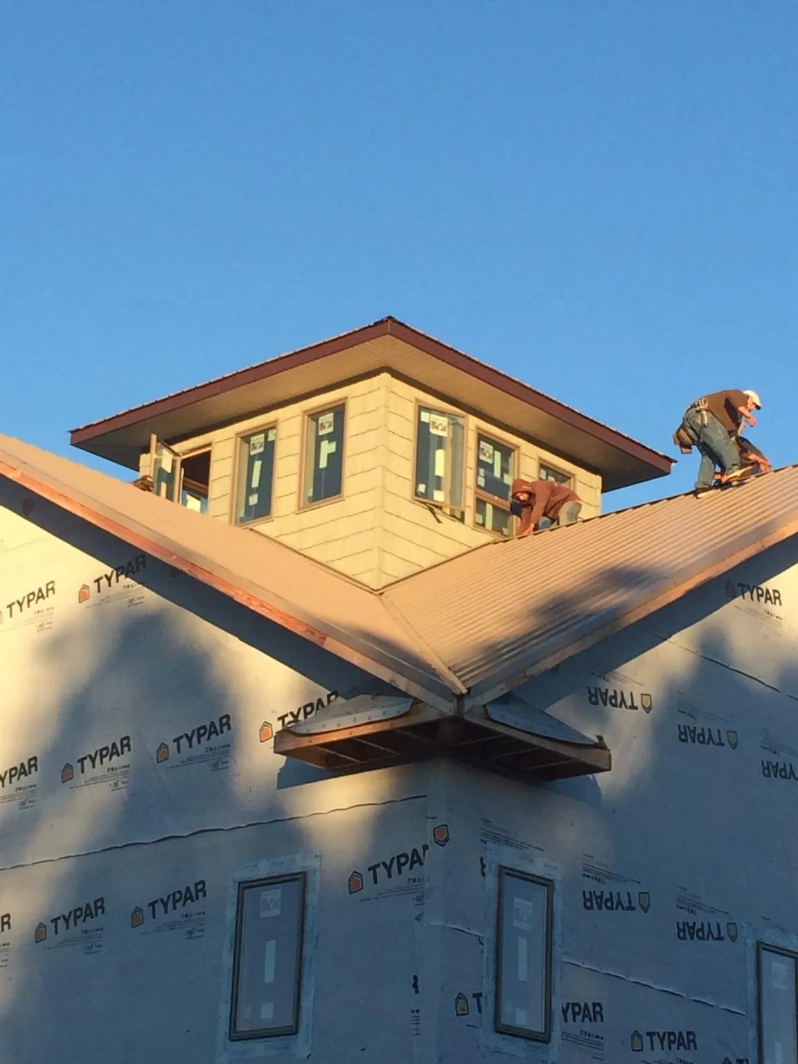 Roofers working around a rooftop cupola on a new metal roof at sunset — Roof Waterproofing in Grassflat by Roofing Brothers